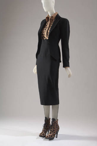 Black suit with fitted peplum jacket, narrow below-the-knee skirt, leopard pattern body suit an…