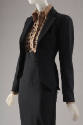 ¾ view of black suit with jacket unbuttoned showing collar and button front of leopard print bo…