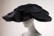 Large semicircular hat in black silk gazar with oversized petals for brim