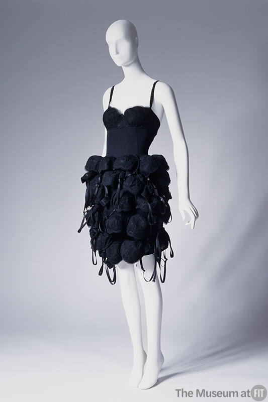 Short black slip style dress with tubular skirt covered from waist to hem with multiple black b…