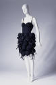 Short black slip style dress with tubular skirt covered from waist to hem with multiple black b…