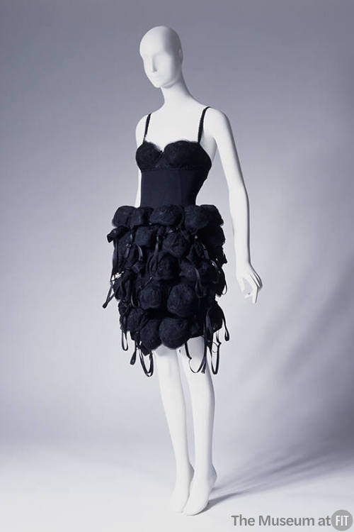 Short black slip style dress with tubular skirt covered from waist to hem with multiple black b…