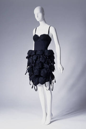 Short black slip style dress with tubular skirt covered from waist to hem with multiple black b…