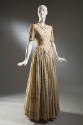 Cream full-length dress with corded pinstripes alternating with navy blue; fitted torso and ful…