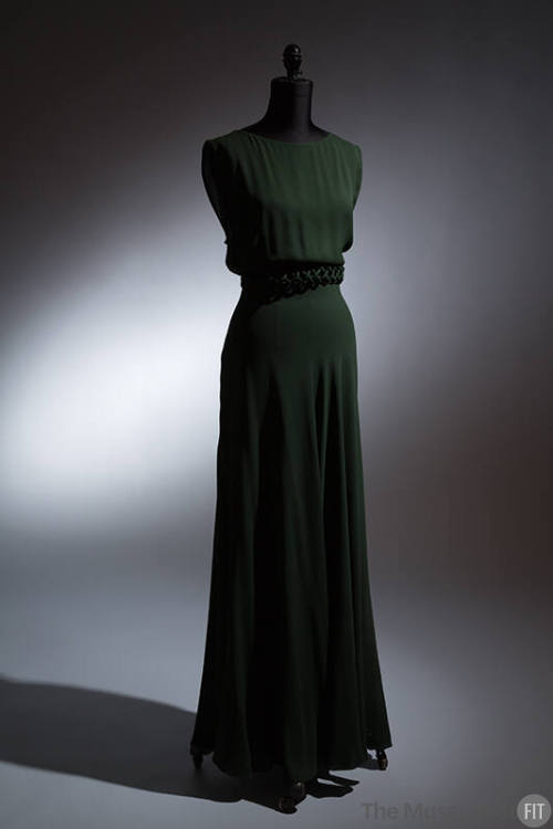 Dark green sleeveless floor length dress with lattice design piping at waist