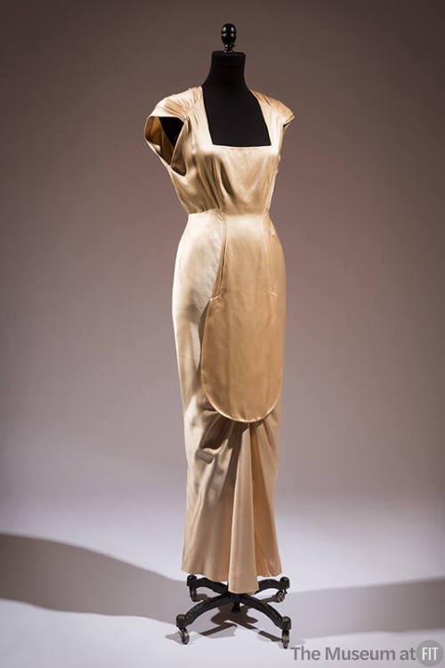 Beige floor length evening dress with square neckline, cap sleeves and front oval plastron pane…