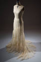 Off-white sleeveless evening dress with flared skirt and spiral ruffle from hip to train