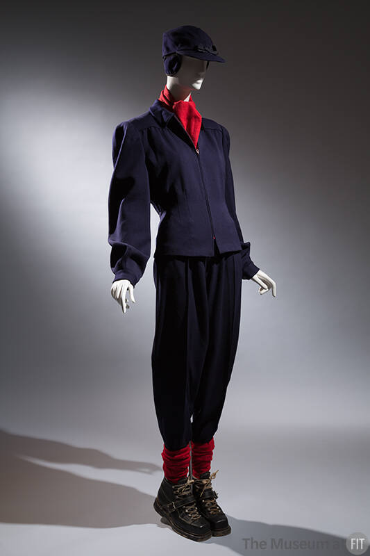 Ski ensemble; navy jacket, pants, and hat with coordinating black ski boots, socks, and red sca…