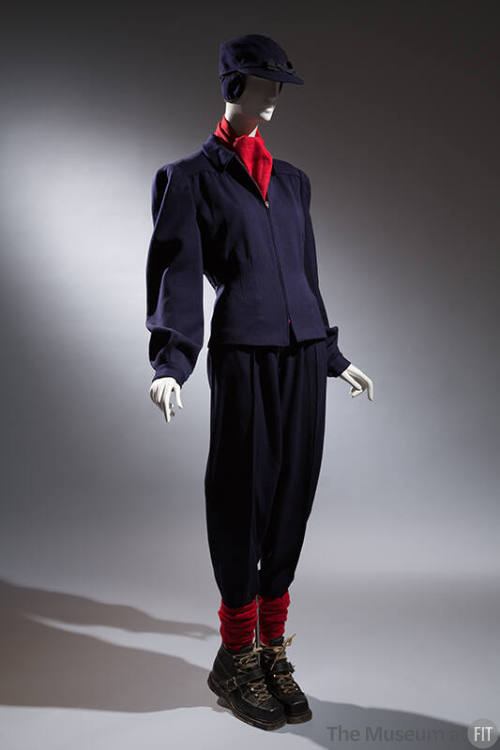 Ski ensemble; navy jacket, pants, and hat with coordinating black ski boots, socks, and red sca…