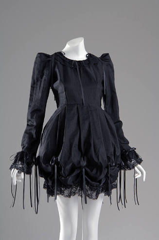 Black long sleeve mini dress with draped poof skirt and bows with long draping ends and lace tr…