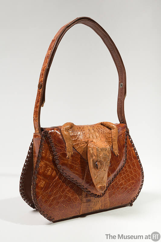 Brown alligator skin handbag with alligator head and paws at flap closure, shoulder strap