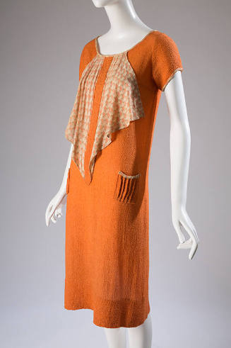 Orange short sleeve dress with triangular cascade of patterned orange and tan fabric from neckl…
