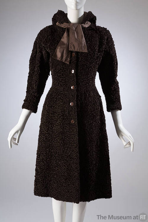 Brown, knee length hooded coat with wide, lightly padded shoulders and self tie bow at collar