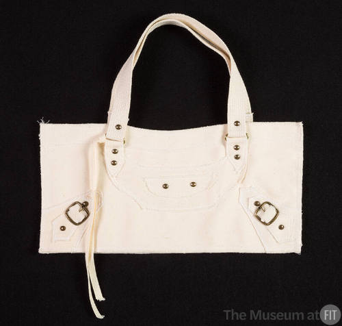 White handbag with decorative brass studs and buckles