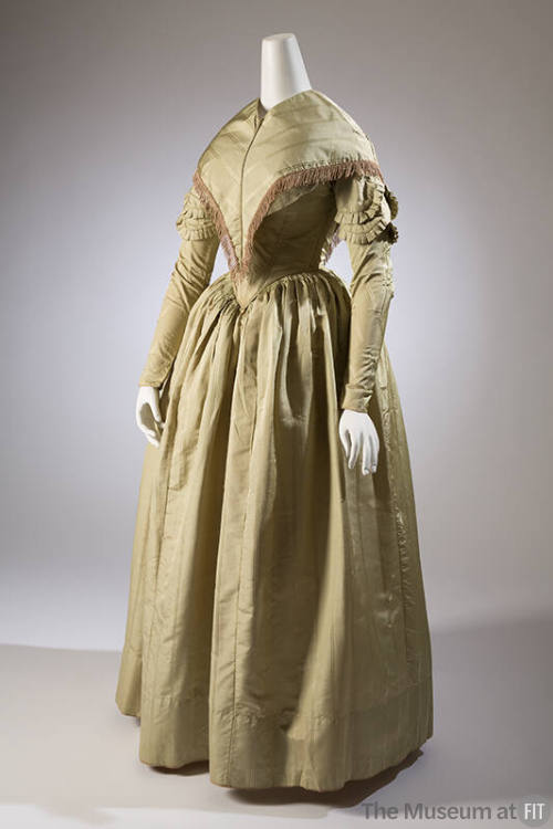 Pale green floor length dress with long sleeves trimmed in pleats, full cartridge pleated skirt…