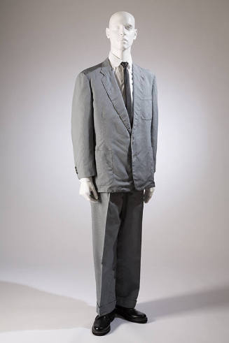 Man’s grey suit of notched lapel jacket with three patch pockets and matching pants dressed wit…