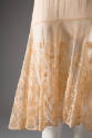 Detail view of beige slip showing floral lace on skirt flounce 