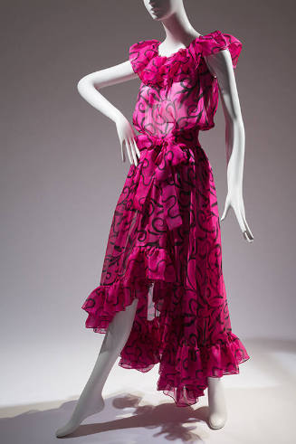 Pink sheer with black sqiggle print, ruffled neckline, bow at waist and high / low skirt with r…