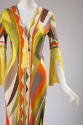 Detail of yellow, orange, off-white, brown and green abstract print dress with yellow tassel at…