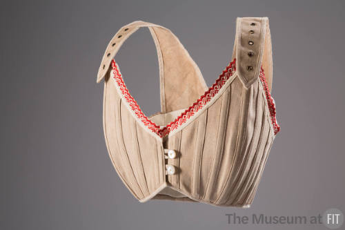 Beige brassiere with red and white ribbon top trim, adjustable straps with gromets and two butt…