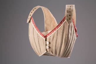 Beige brassiere with red and white ribbon top trim, adjustable straps with gromets and two butt…
