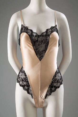 Peach teddy with wide black lace bands at v-shaped neckline and high cut leg side panels