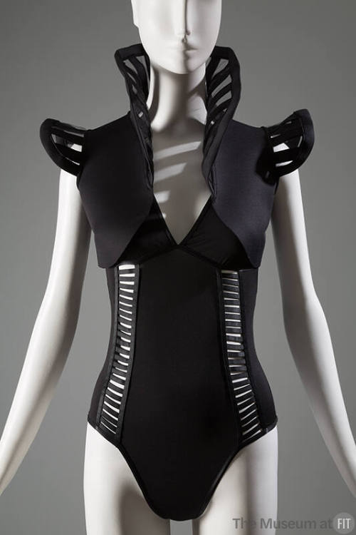 Black body suit with rib like cut-out design, low V neckline, and double shoulder sraps with bo…