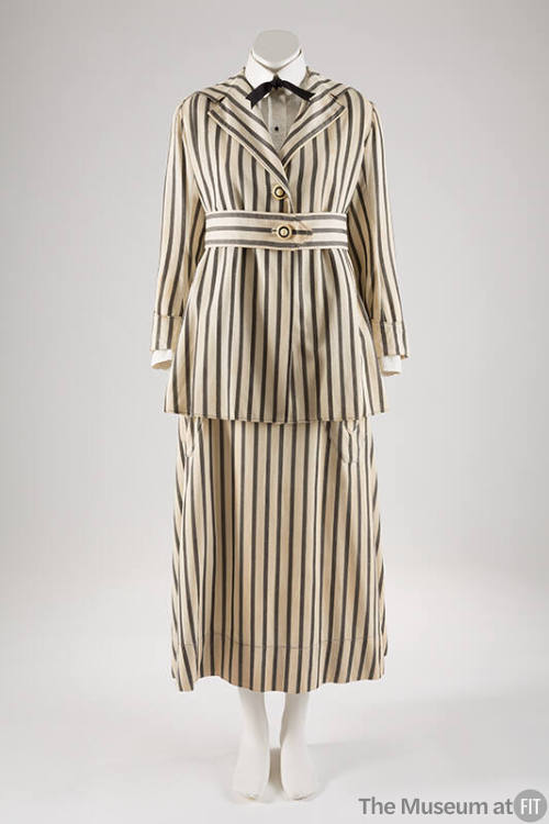 White and vertical black striped suit with below hip length two-button jacket, matching belt an…