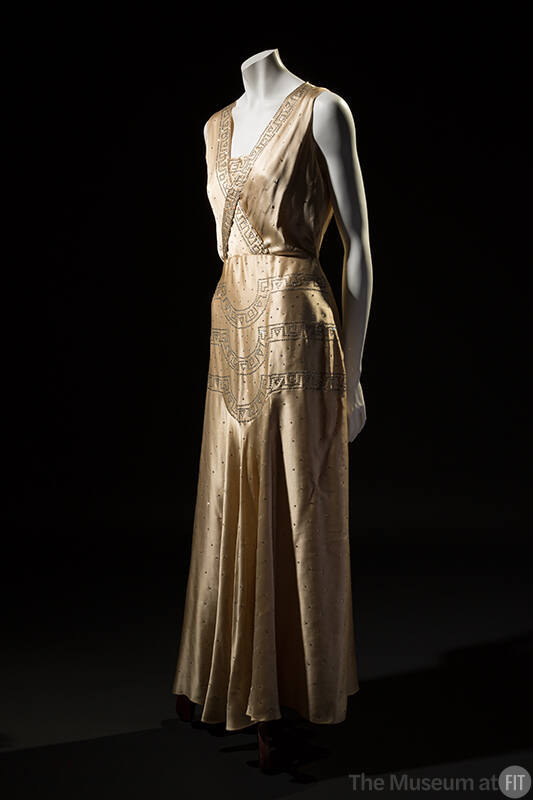 Ivory silk satin sleeveless floor length evening dress with Art Deco border design crossed acro…