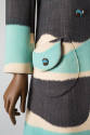 Close up of coat printed in horizontal irregularly curved blue, grey, and white bands with roun…