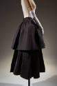 Side view of black layered, tiered cape dressed on mannequin as skirt