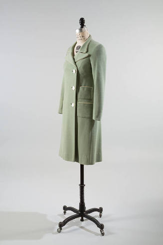 Pale green coat with three button closure and two patch pockets on right hip
