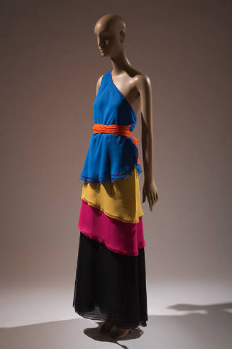 Blue, yellow, pink, black layered one shoulder floor length dress with orange belt