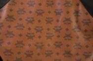 Detail of black MCM logo print on brown jacket