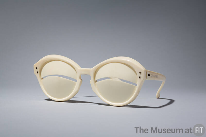Ivory sunglasses with curved slit at eye center; gold metal studs at temples; stamped Depose an…