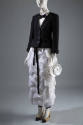 Ensemble of black jacket, white shirt, black bow tie, white ruffled ankle length skirt, beige p…