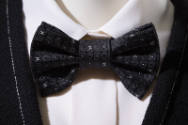 Detail view of black and white ensemble’s black silk jacquard bow tie with small white CC Chane…