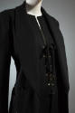 Black shawl collar jacket over black deep V-neck top with lace up front closure and gold gromme…