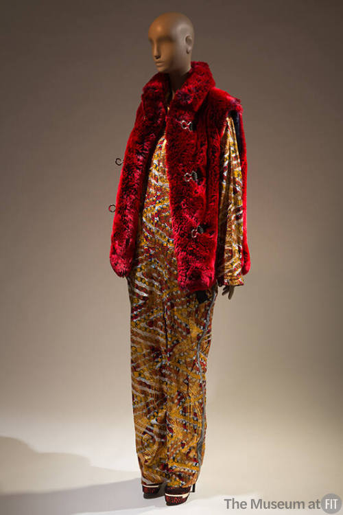 Yellow multicolor pattern long sleeve jumpsuit under open red faux fur vest with three loop clo…