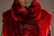 Detail view of red faux fur vest showing vest fastened closed with silver metal loop closures a…