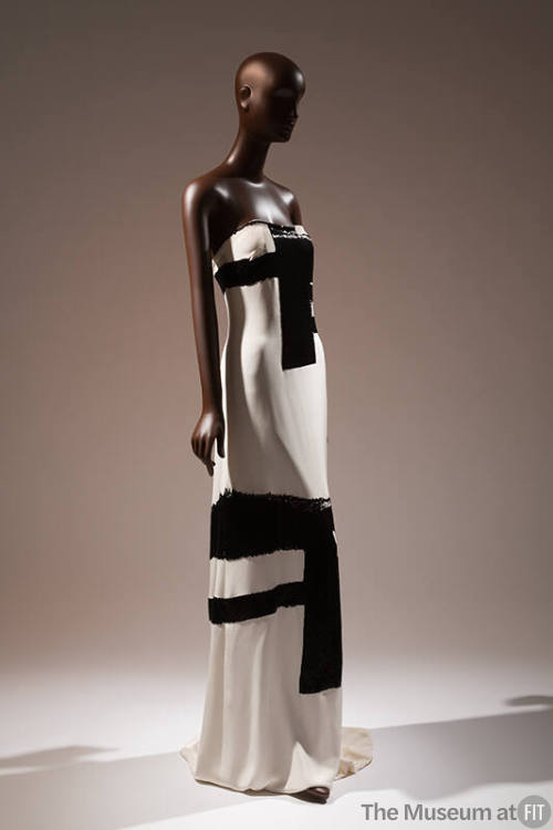 ¾ view of white strapless floor length evening dress with thick black brushwork motifs througho…