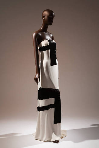 ¾ view of white strapless floor length evening dress with thick black brushwork motifs througho…