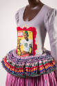 Detail view of grey top and skirt showing embroidery and applique around magazine print and pep…