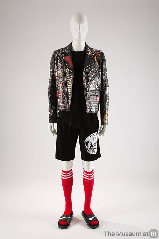 Man’s black leather jacket with graffiti paint, black top, black shorts with white skull appliq…