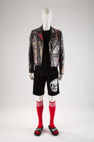 Man’s black leather jacket with graffiti paint, black top, black shorts with white skull appliq…