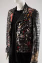 ¾ view of black leather jacket ensemble showing allover graffiti paint of multicolor shapes and…