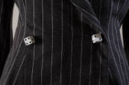 Detail view of grey pinstriped suit showing two front buttons in the shape of dice