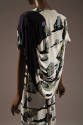 Back detail of off-white dress printed with gray stones with black shadows and yellow symbols, …