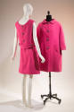Pink skirt suit shown from the back: sleeveless blouse features three large buttons and a marti…
