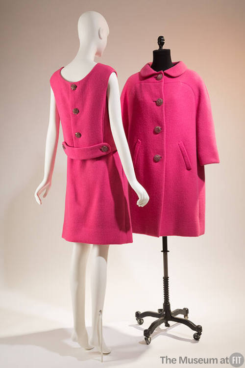 Pink skirt suit shown from the back: sleeveless blouse features three large buttons and a marti…